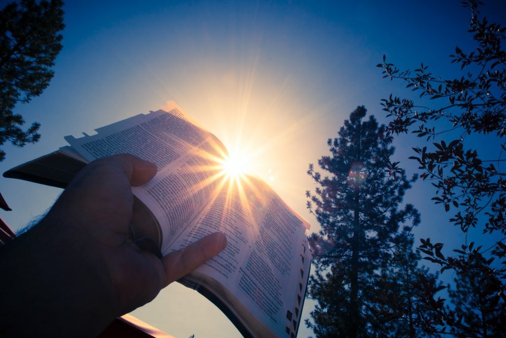 O que significa sonhar com Cama? Números e Tipos de sonhos 4 pessoa segurando a bíblia para o sol